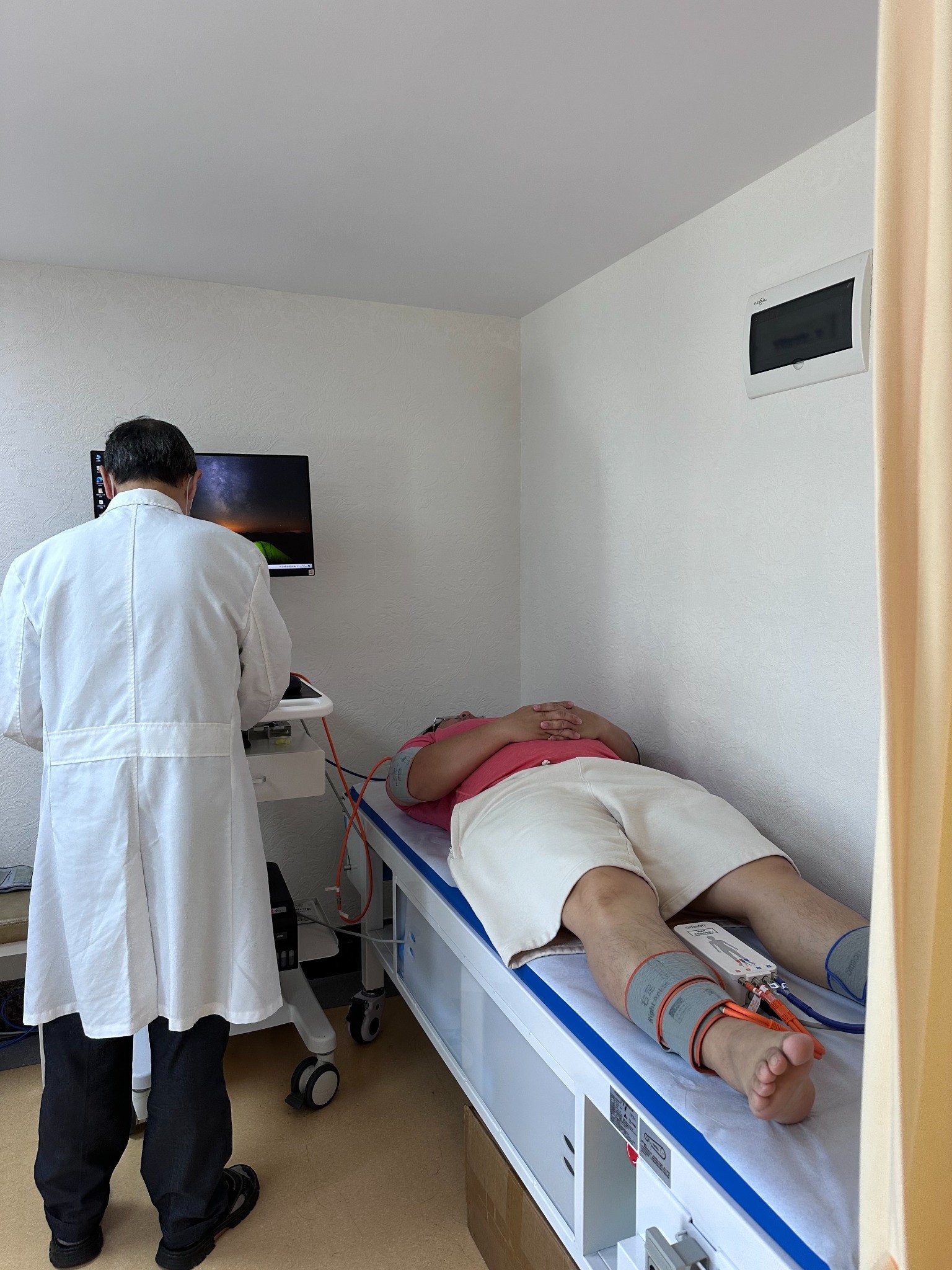 A hospital clinician assisting with a clinical examination using limb cuffs