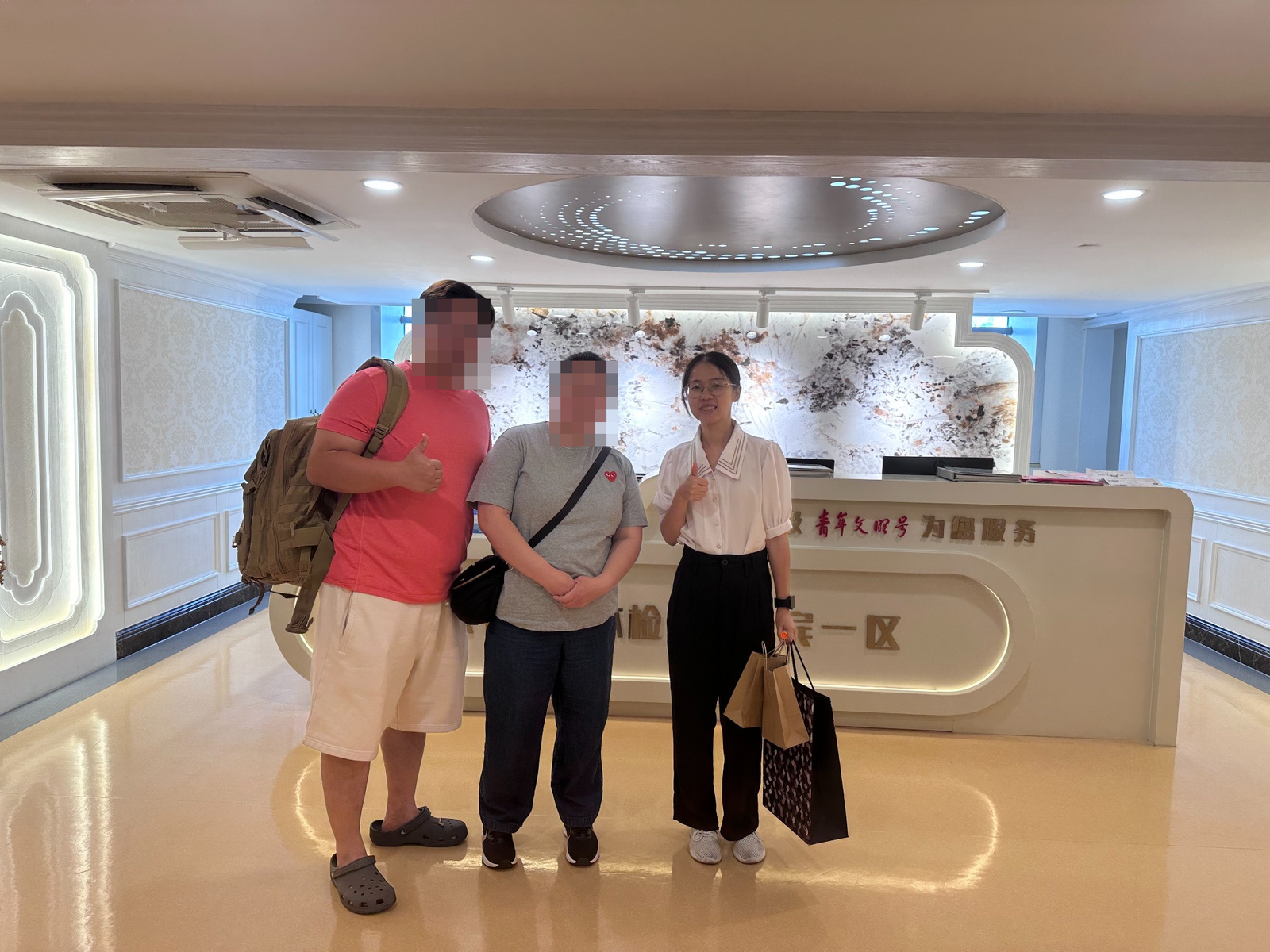 Two visitors with their faces obscured beside English-speaking companion Lucy at the hospital